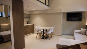 Un intérieur moderne comprenant un coin repas, un canapé, une cuisine et un téléviseur fixé au mur.