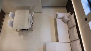Un intérieur moderne avec un canapé d’angle, une table à manger et des chaises, et un design minimaliste.