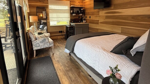 A modern bedroom with a large bed, a small desk, a chair, and a window with a view.