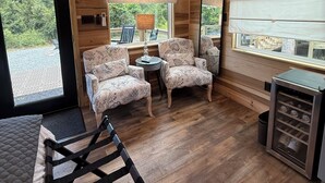 A modern interior with wooden paneling, a sofa, two armchairs, a small table, and a wine cooler.