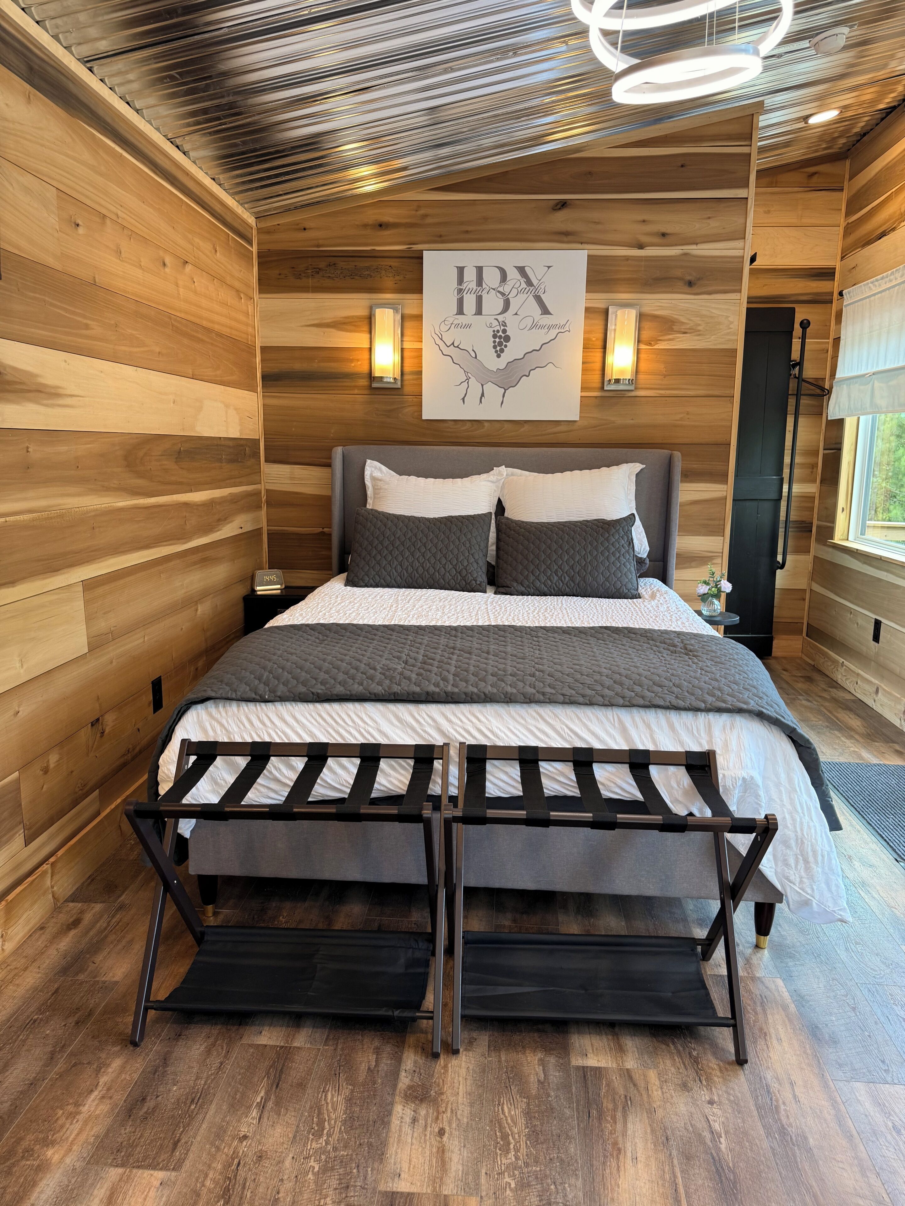 Ein Zimmer mit Holzwänden, einem Bett, einem an der Wand befestigten Schild und einem Fenster.
