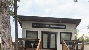 A building with a wooden deck, a staircase, and a barrel.