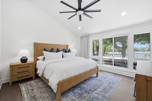 A bedroom with a wooden bed, a nightstand with a lamp, a large window with a view, and a ceiling fan. - Completely Renovated - Ideal for up to 16 with private pool, hot tub, arcade and great amenities! (Denver)