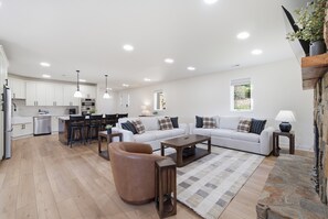 A spacious living area with a sofa set, a coffee table, and a dining area with chairs and a kitchen in the background. - Completely Renovated - Ideal for up to 16 with private pool, hot tub, arcade and great amenities! (Denver)
