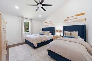 A bedroom with two beds, a ceiling fan, a window with curtains, and wooden paddles on the wall. - Completely Renovated - Ideal for up to 16 with private pool, hot tub, arcade and great amenities! (Denver)