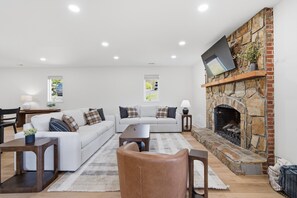 Ein stilvolles Wohnzimmer mit Kamin aus Stein, weißen Sofas und einem Couchtisch.