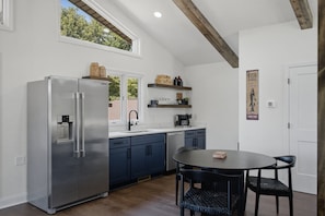 A modern kitchen with a stainless steel refrigerator, a sink, and a dining area with a round table and chairs. - Completely Renovated - Ideal for up to 16 with private pool, hot tub, arcade and great amenities! (Denver)