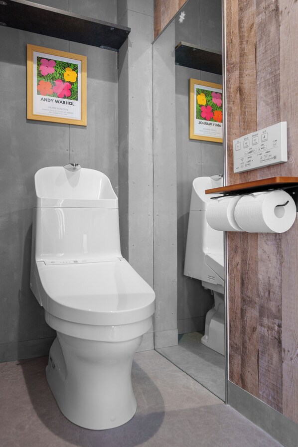 A modern bathroom with a toilet, a wooden-framed picture of flowers, and a toilet paper holder.