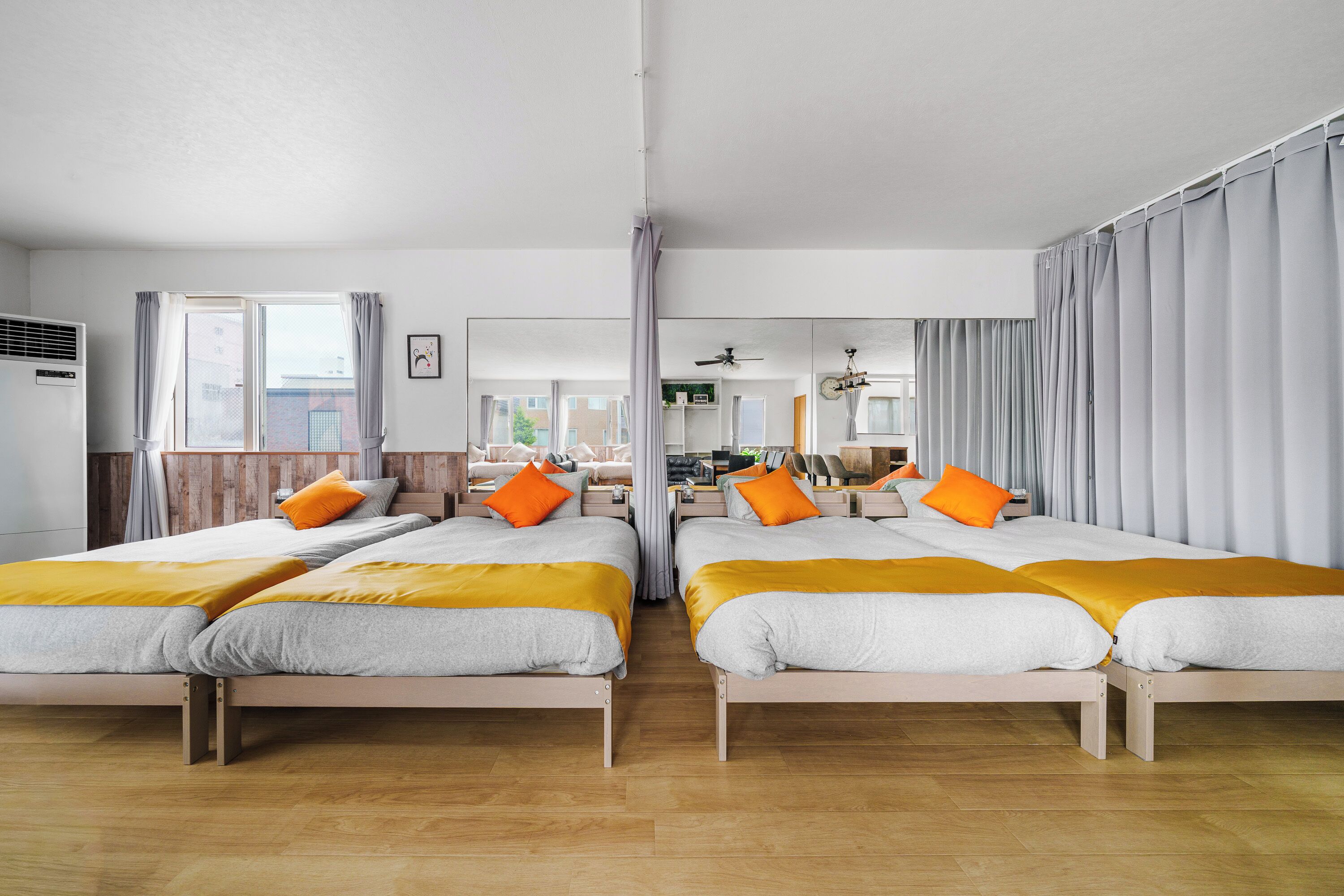 Habitación de hotel con dos camas, piso de madera, un ventanal y vista a la ciudad.