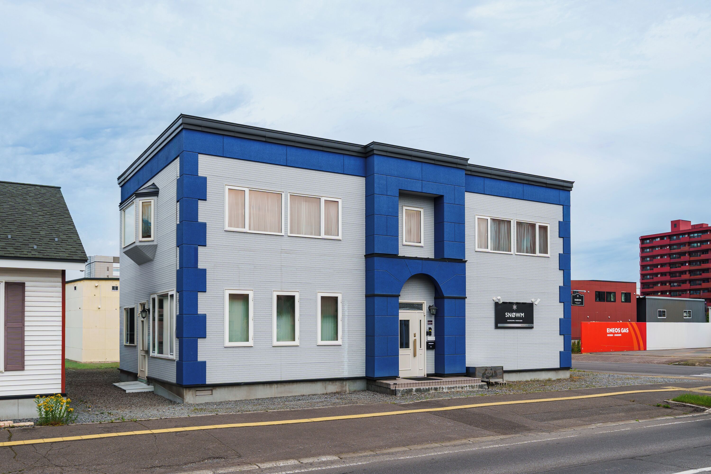 A two-story building with a blue and white facade, a front entrance, and a sign that reads 'SNOWM.'