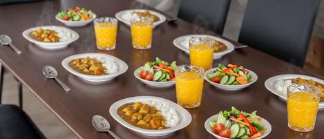 Una mesa de comedor con platos de comida, vasos de jugo de naranja y cucharas.