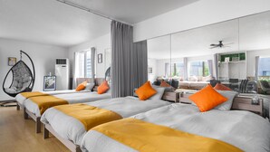 Habitación de hotel con dos camas, una silla colgante, un escritorio y un espejo grande.