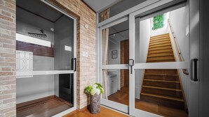 Un interior moderno con una pared de ladrillo, una escalera de madera y una puerta de cristal que da a un baño.