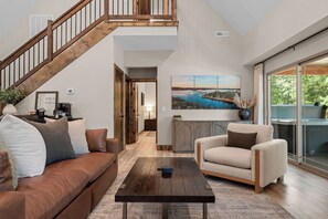 Una sala de estar moderna con una escalera, una mesa de centro, un sofá y una silla.