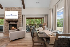 Una sala de estar moderna con chimenea, comedor y ventanas amplias.