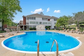 Ein Swimmingpool mit Liegestühlen, ein Gebäude mit Garage und blauer Himmel.
