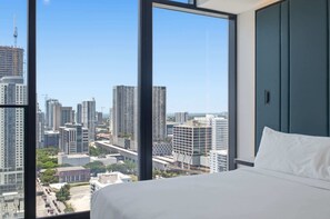 Ein Hotelzimmer mit großem Fenster und Blick auf die Stadt, einem Bett und einem Kleiderschrank.