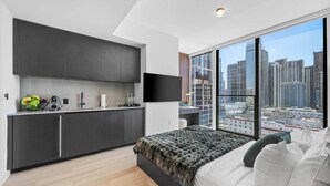 A modern bedroom with a large bed, a city view, a kitchenette, and a flat-screen TV. - Elite E11EVEN Grand Suite Rooftop Pool and City Views (Miami)