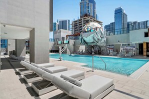 A rooftop pool with lounge chairs, a large glass building in the background, and a unique sculpture. - Elite E11EVEN Grand Suite Rooftop Pool and City Views (Miami)