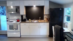 Cocina compacta con microondas, estufa, fregadero y refrigerador.