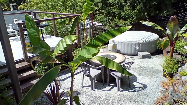 Un patio con una mesa redonda, sillas y una zona de estar cubierta.