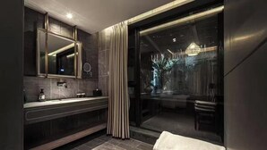 Une salle de bain moderne avec un grand miroir, un meuble-lavabo et une porte en verre donnant sur un balcon.