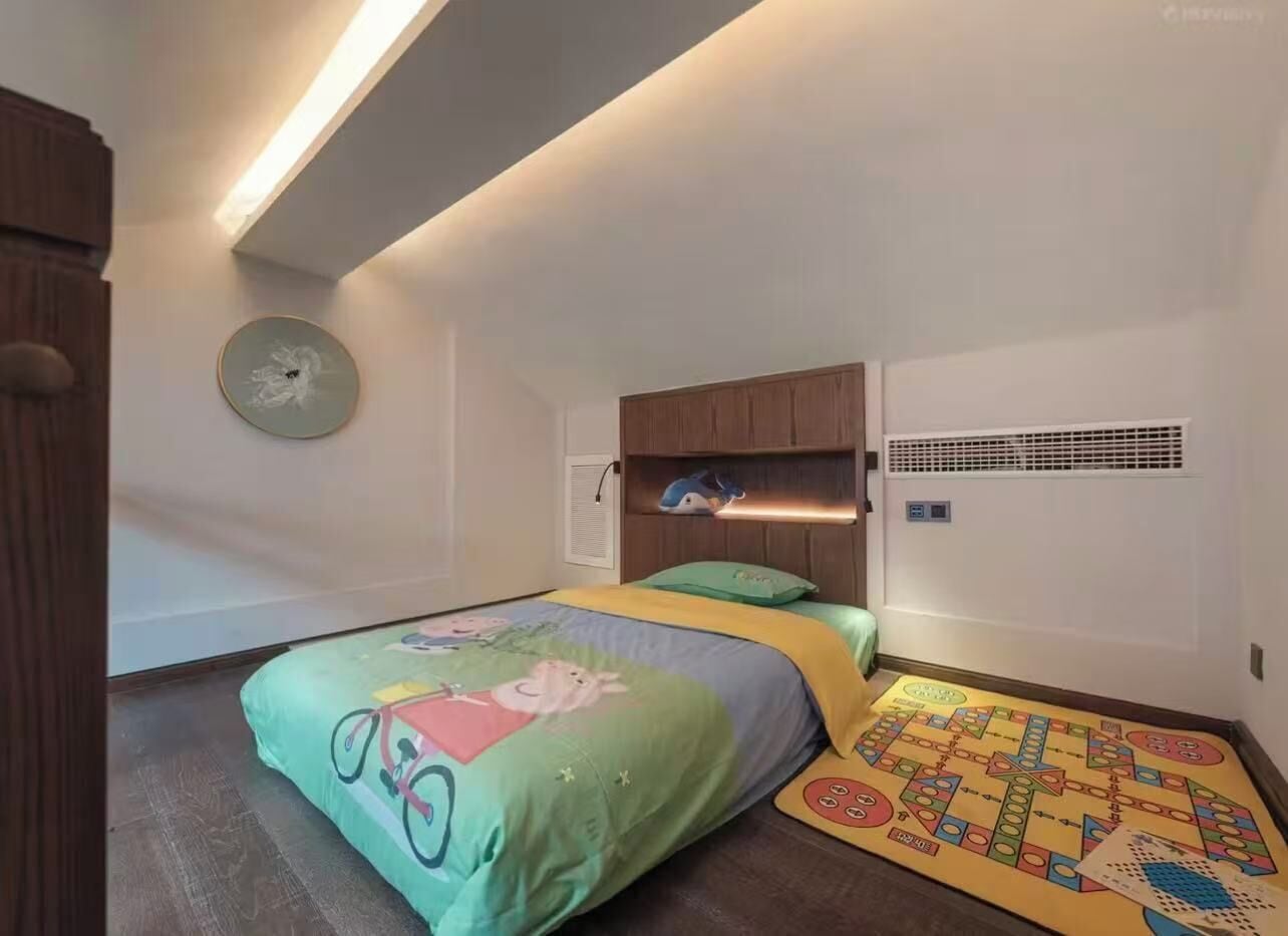 Un dormitorio con dos camas, un reloj de pared, una estantería con juguetes y un sistema de ventilación.