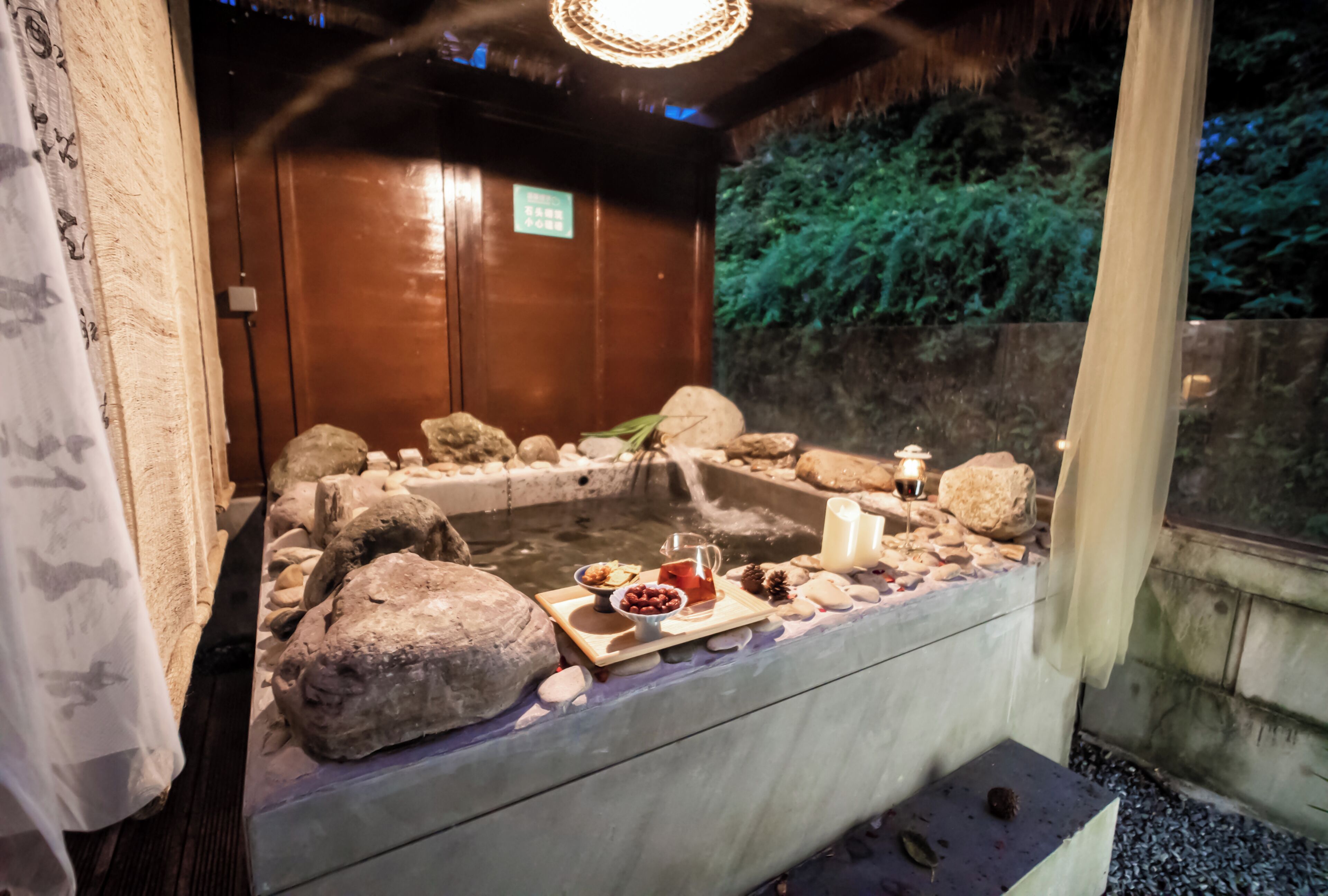 Zona de bany termal amb pedres, una espelma i un plat amb aperitius.