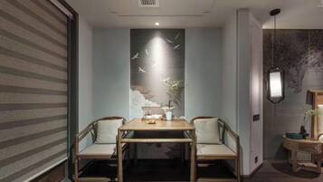 A room with a dining table and chairs, a wall with a mural, a ceiling vent, and a hanging light fixture.
