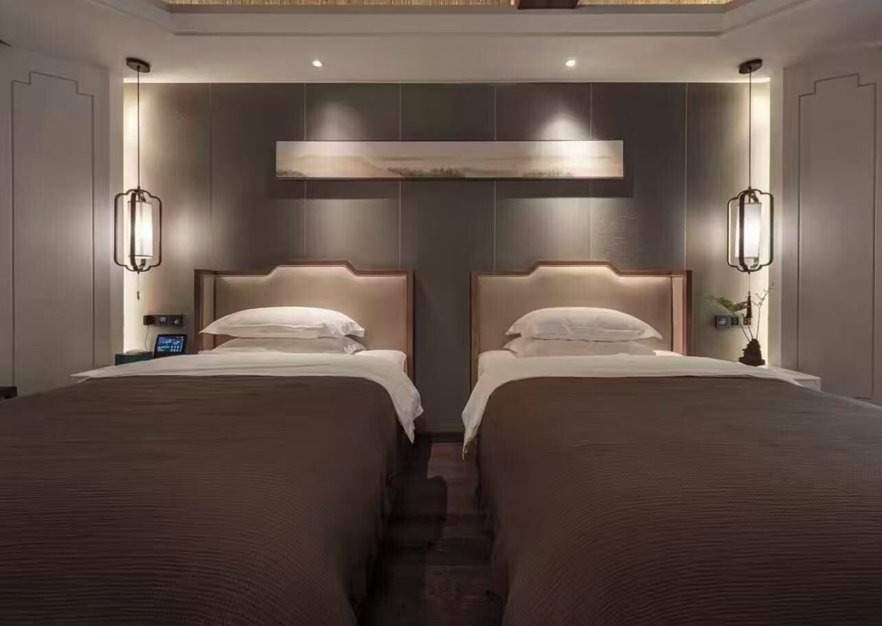 Habitación de hotel con dos camas, un reloj digital y una obra de arte en la pared.