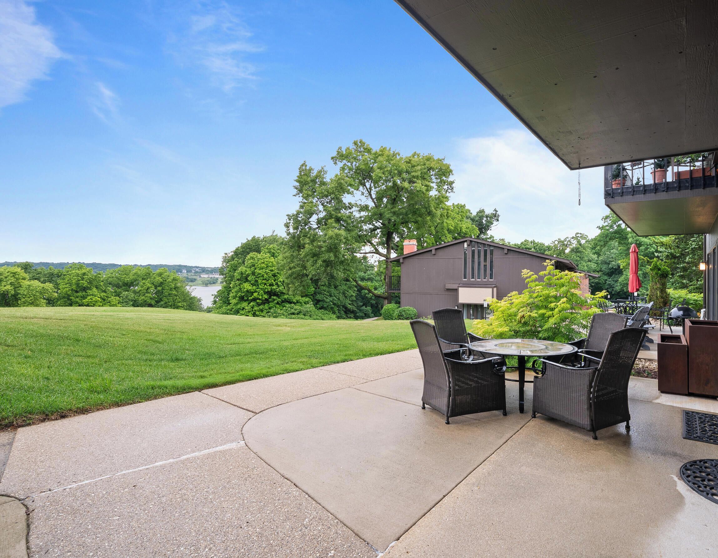 Un patio exterior con mesa y sillas, una parrilla y vistas a una casa y el paisaje.