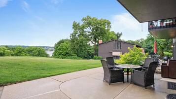 Un patio exterior con mesa y sillas, una parrilla y vistas a una casa y el paisaje.