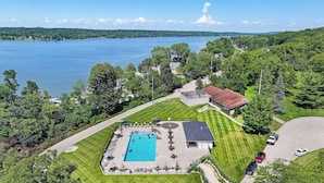 Ein Luftbild eines Anwesens mit Swimmingpool, überdachter Terrasse und Blick auf ein großes Gewässer.