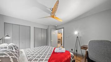 Un dormitorio con cama, escritorio, silla, ventilador de techo y armario.