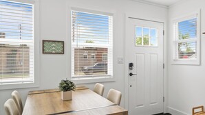 Una habitación con una mesa de comedor de madera, sillas, una planta en maceta y una puerta con un ventanal arriba.
