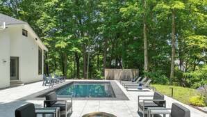 A swimming pool with lounge chairs, a small building, and a forested area. - Fontana Home With Pool and Hot Tub Minutes from the Lake (Fontana-on-Geneva Lake)