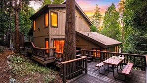 Een chalet met een terras, houten leuningen en een picknicktafel.