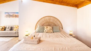A bedroom with a wooden ceiling, a bed with a large woven headboard, a sofa, and two bedside lamps. - Coqueta Casita de Mercedes (Tacoronte)