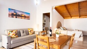 A modern living room with a wooden dining table, sofa, and a cityscape painting. - Coqueta Casita de Mercedes (Tacoronte)