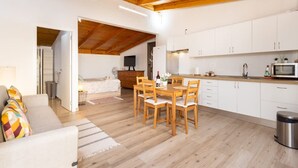 A modern kitchen with white cabinets, a wooden dining table, and a TV mounted on the wall. - Coqueta Casita de Mercedes (Tacoronte)
