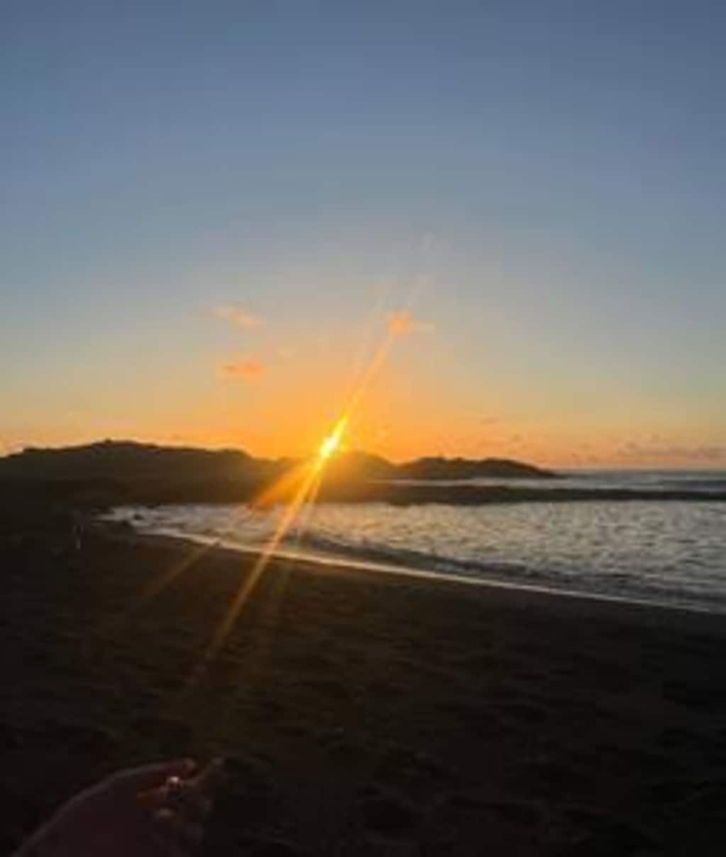 A beach at sunset with a clear sky.