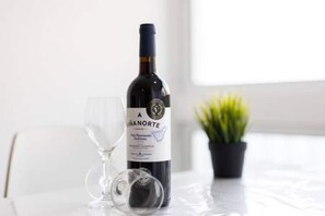 Uma garrafa de vinho, uma taça de vinho e um vaso de planta sobre uma mesa.