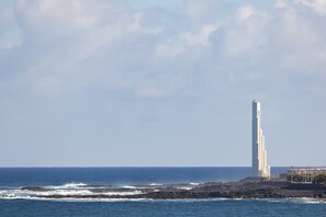 Blick auf die Küste mit einem hohen, weißen Gebäude, möglicherweise einem Leuchtturm, in der Nähe des Wassers.
