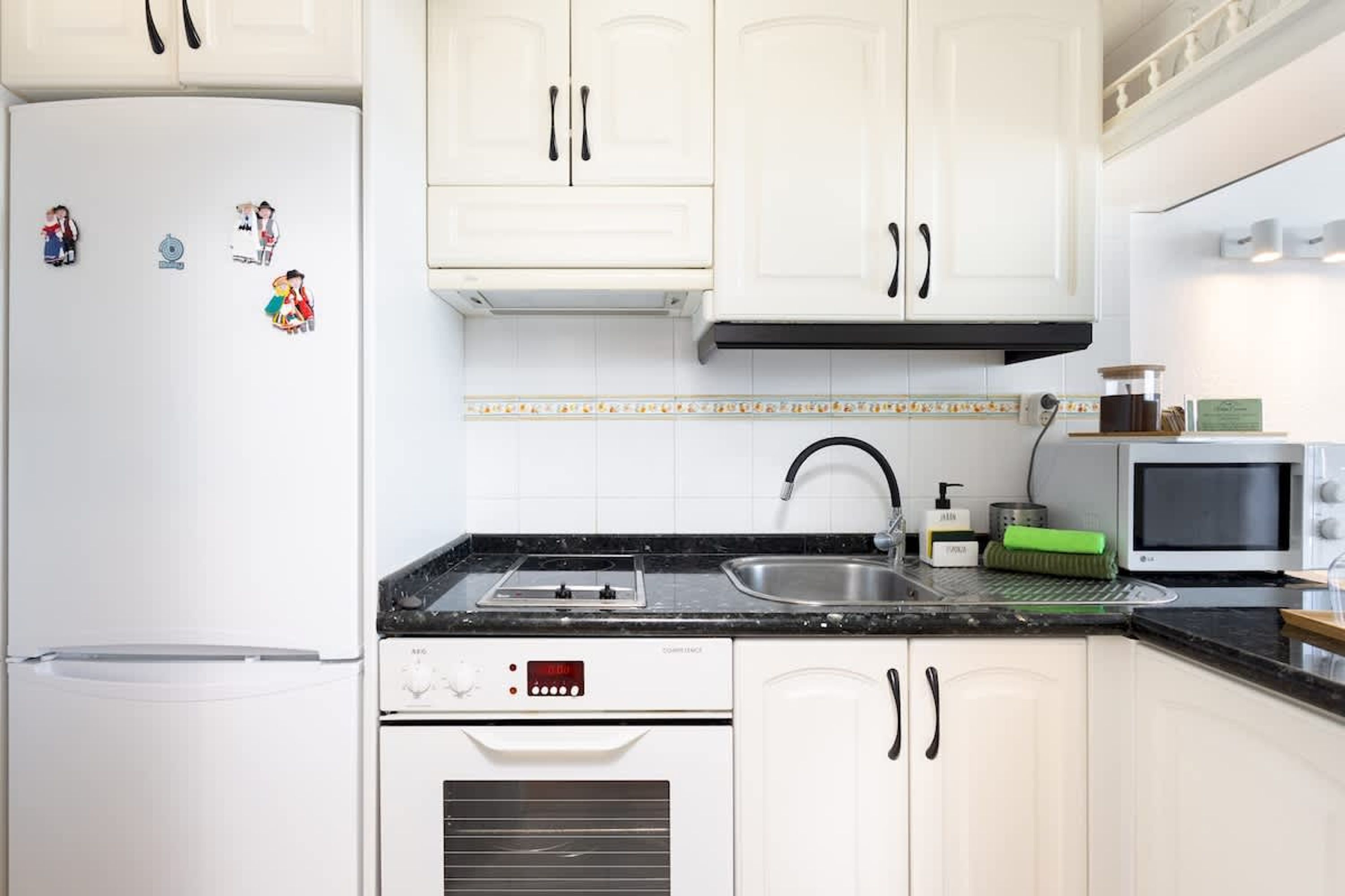 A kitchen with white cabinets, a stainless steel sink, a microwave, and a built-in oven.