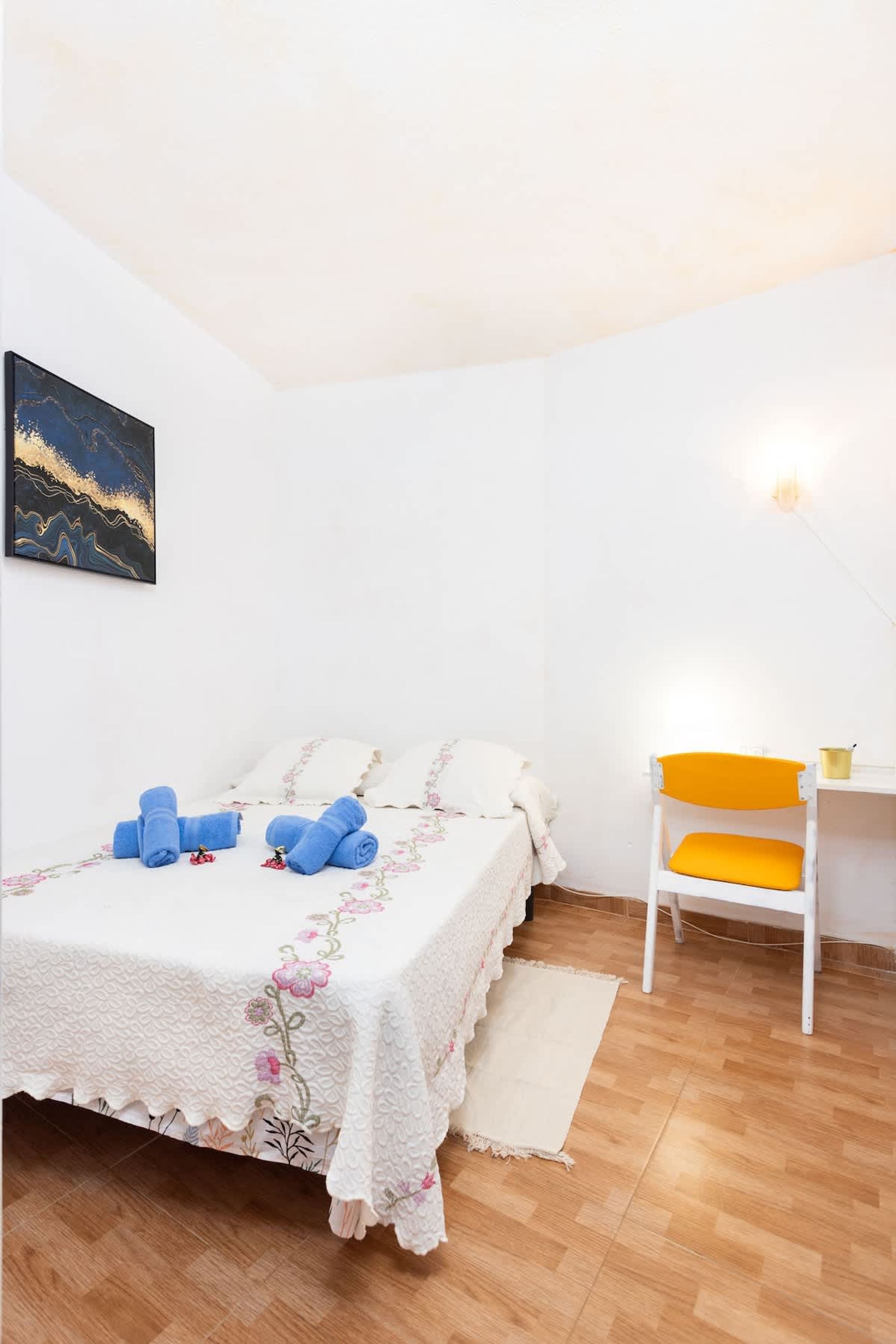 Une chambre à coucher avec un lit, une chaise, un bureau et une lampe.