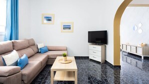 Ein modernes Wohnzimmer mit einer Couch, einem Fernseher und einem kleinen Tisch.