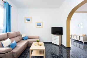 Ein modernes Wohnzimmer mit einer Couch, einem Fernseher und einem kleinen Tisch.