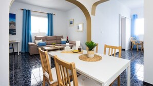 Ein Essbereich mit einem weißen Tisch, Holzstühlen und einem Blumentopf.