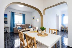 Ein Essbereich mit einem weißen Tisch, Holzstühlen und einem Blumentopf.
