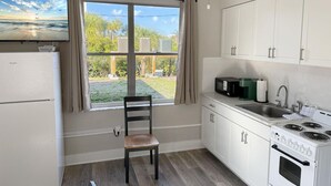 A kitchen with a window view, a refrigerator, a microwave, a stove, and a chair. - Venice Villas San Marco - Golden Beach (Venice)